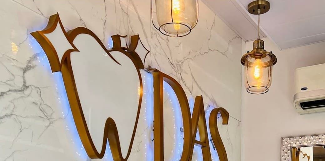 The illuminated gold DAS logo on the marble reception wall of DAS Dental Clinic & Diagnostic Center